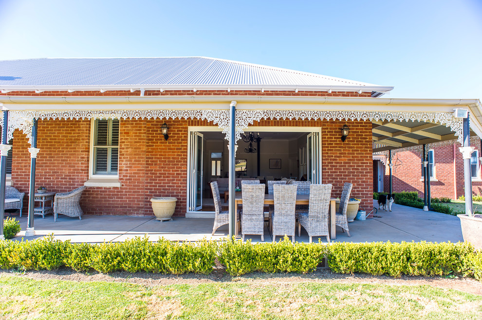 Photo of a traditional backyard verandah in Other with concrete slab and an awning.