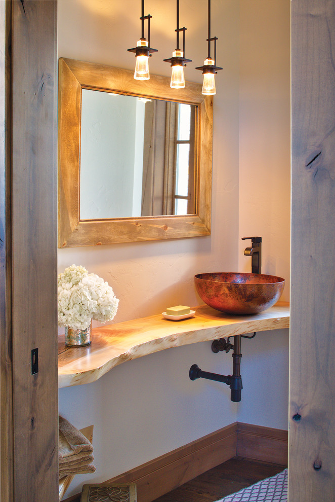 This is an example of a mid-sized modern powder room in Denver with open cabinets, beige walls, medium hardwood floors, a vessel sink, wood benchtops, brown floor and yellow benchtops.