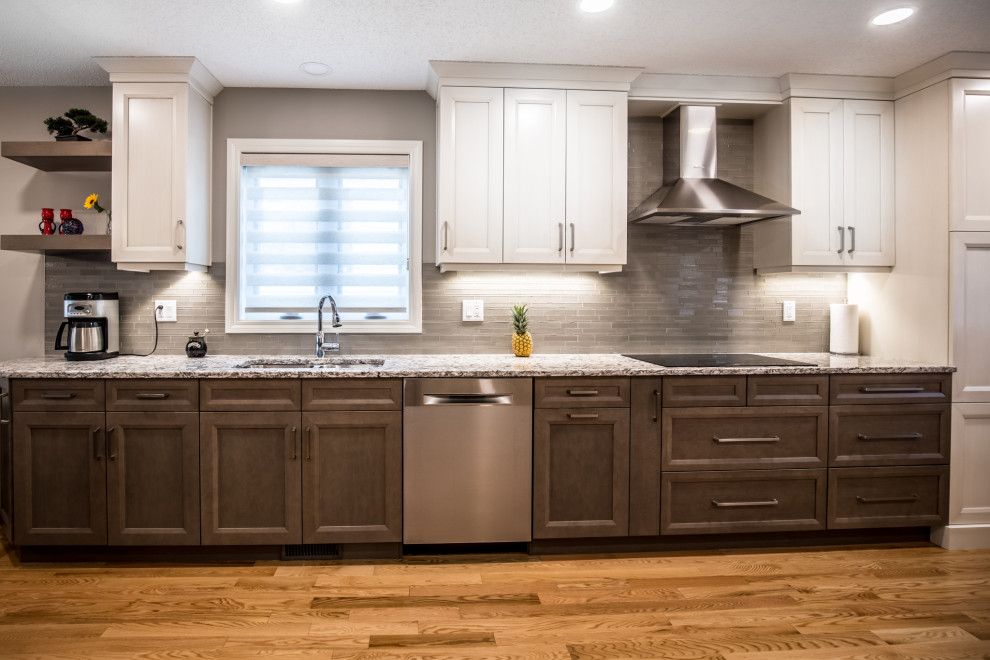 Mid-sized transitional single-wall medium tone wood floor and beige floor eat-in kitchen photo in Edmonton with an undermount sink, shaker cabinets, beige cabinets, granite countertops, beige backsplash, glass tile backsplash, stainless steel appliances, an island and beige countertops