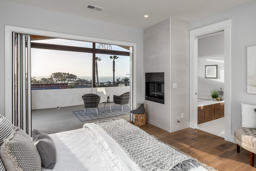 Design ideas for a transitional master bedroom in San Diego with grey walls, medium hardwood floors, a ribbon fireplace and brown floor.