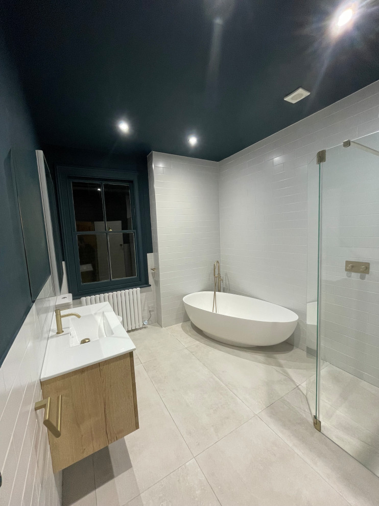 Inredning av ett modernt stort badrum för barn, med släta luckor, skåp i ljust trä, ett fristående badkar, en öppen dusch, blå väggar, klinkergolv i porslin, grått golv och med dusch som är öppen