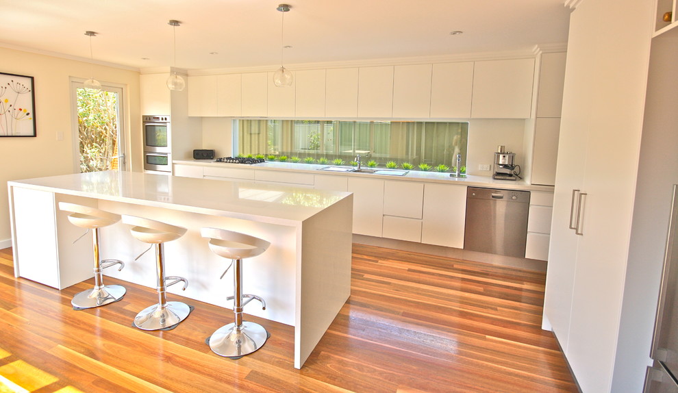 Inspiration for a large contemporary l-shaped eat-in kitchen in Sydney with an undermount sink, flat-panel cabinets, white cabinets, quartz benchtops, white splashback, stone slab splashback, stainless steel appliances, medium hardwood floors and with island.