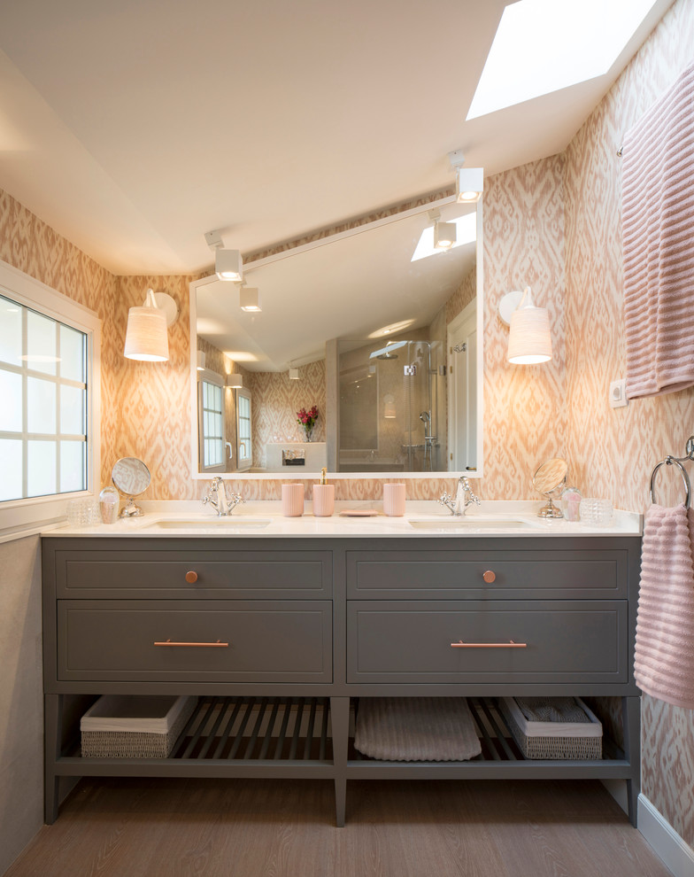 Photo of a large transitional kids bathroom in Bilbao with raised-panel cabinets, grey cabinets, a curbless shower, a wall-mount toilet, pink walls, laminate floors, an undermount sink, engineered quartz benchtops and a hinged shower door.