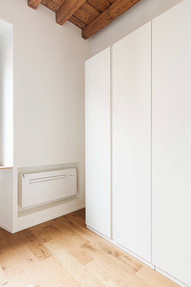 ミラノにある小さな北欧スタイルのおしゃれな主寝室 (白い壁、淡色無垢フローリング、暖炉なし、茶色い床、板張り天井、全タイプの壁の仕上げ) のインテリア