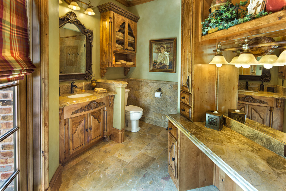 Photo of a mid-sized mediterranean 3/4 bathroom in Dallas with furniture-like cabinets, medium wood cabinets, an alcove shower, a one-piece toilet, beige tile, mosaic tile, beige walls, ceramic floors, a vessel sink and granite benchtops.