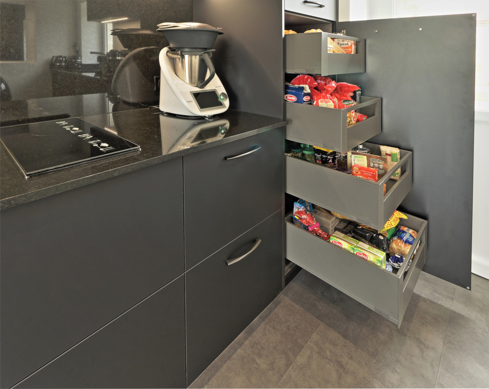 This is an example of an expansive contemporary galley eat-in kitchen in Other with an undermount sink, flat-panel cabinets, black cabinets, quartzite benchtops, black splashback, granite splashback, stainless steel appliances, laminate floors, with island, grey floor and black benchtop.