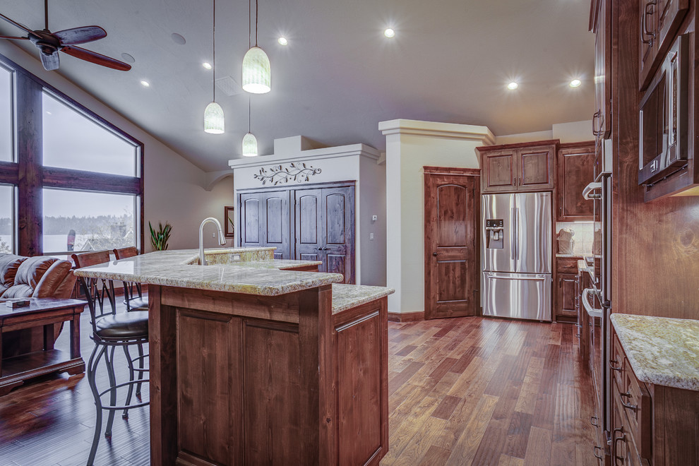 Large mountain style u-shaped medium tone wood floor eat-in kitchen photo in Seattle with an undermount sink, raised-panel cabinets, medium tone wood cabinets, granite countertops, beige backsplash, ceramic backsplash, stainless steel appliances and an island