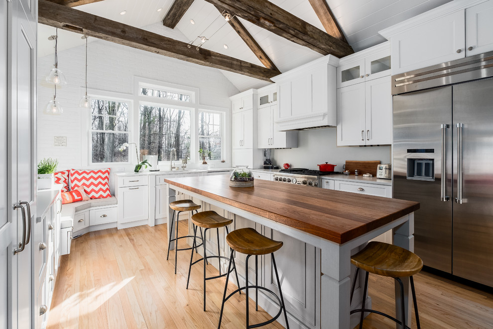 Mid-sized country l-shaped eat-in kitchen in New York with an undermount sink, flat-panel cabinets, white cabinets, quartz benchtops, stainless steel appliances, light hardwood floors and with island.