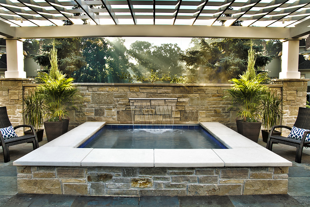 This is an example of a small traditional backyard rectangular aboveground pool in Chicago with a hot tub and natural stone pavers.
