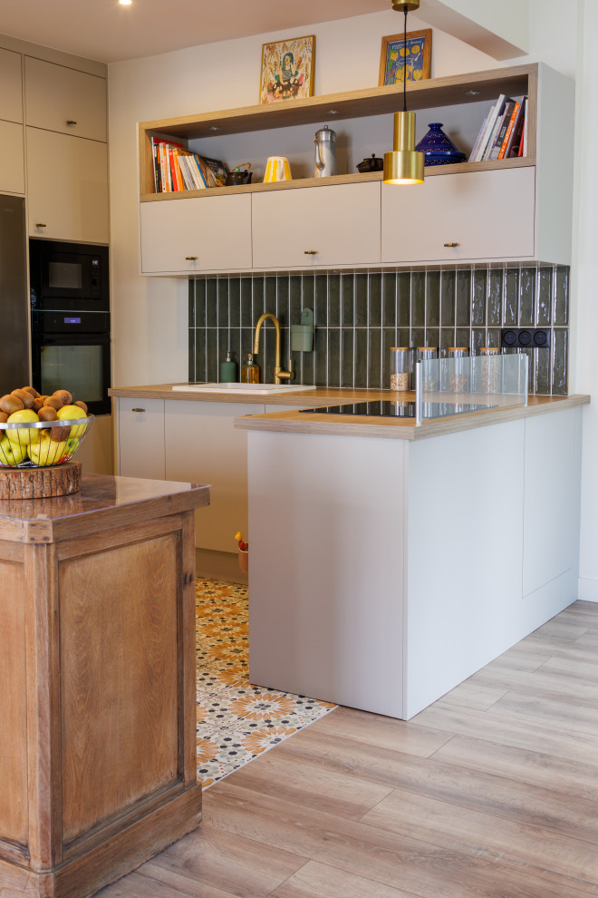Midcentury kitchen in Paris with wood benchtops, green splashback, cement tiles, multiple islands and beige benchtop.