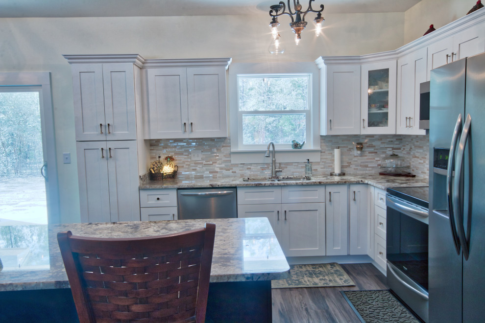Eat-in kitchen - mid-sized l-shaped eat-in kitchen idea with an undermount sink, shaker cabinets, yellow cabinets, granite countertops, glass tile backsplash, stainless steel appliances, an island and white countertops