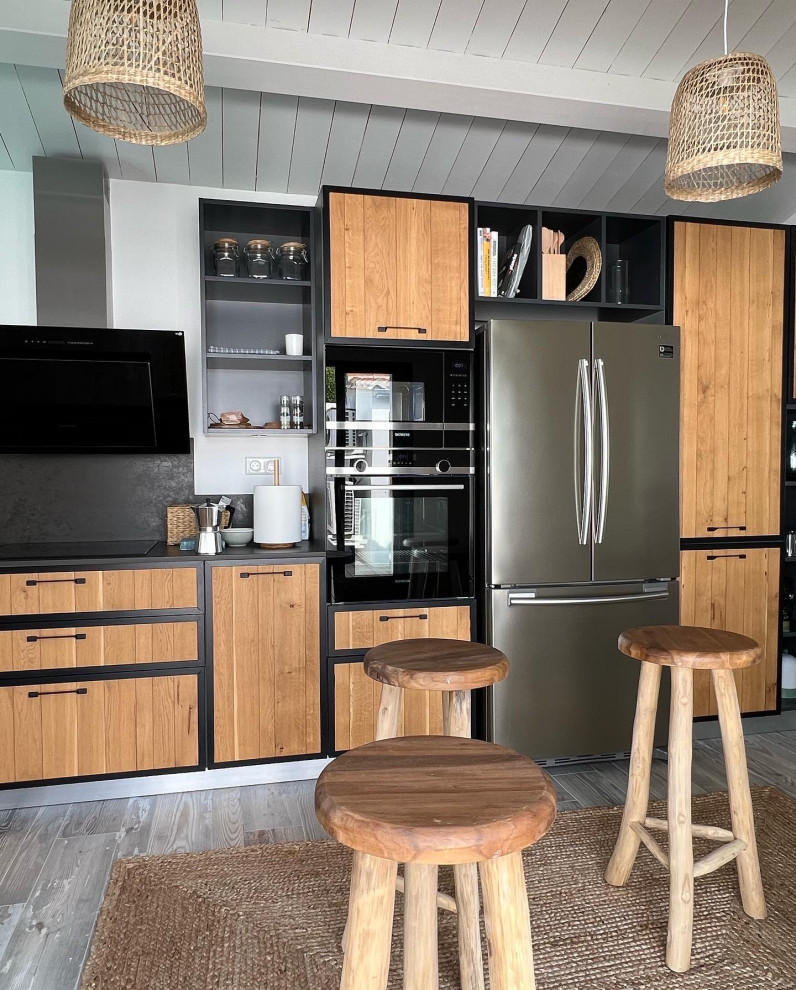 Inspiration for a large contemporary l-shaped open plan kitchen in Other with an integrated sink, beaded cabinets, light wood cabinets, black splashback, black appliances, ceramic flooring, no island, multi-coloured floors, black worktops and exposed beams.