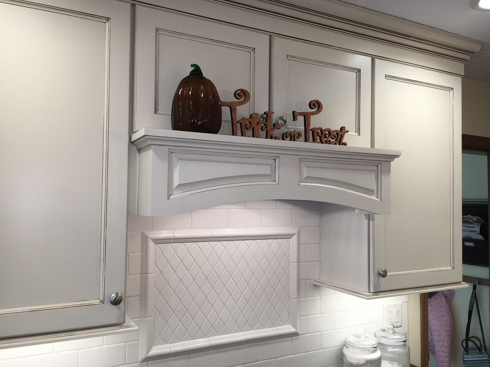 Inspiration for a large transitional medium tone wood floor and brown floor eat-in kitchen remodel with an undermount sink, flat-panel cabinets, white cabinets, granite countertops, white backsplash, porcelain backsplash, stainless steel appliances and an island