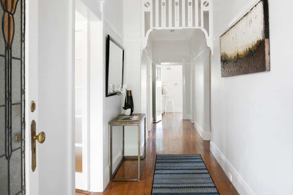 Photo of a transitional entry hall in Sydney with white walls, medium hardwood floors, a single front door, a glass front door and brown floor.