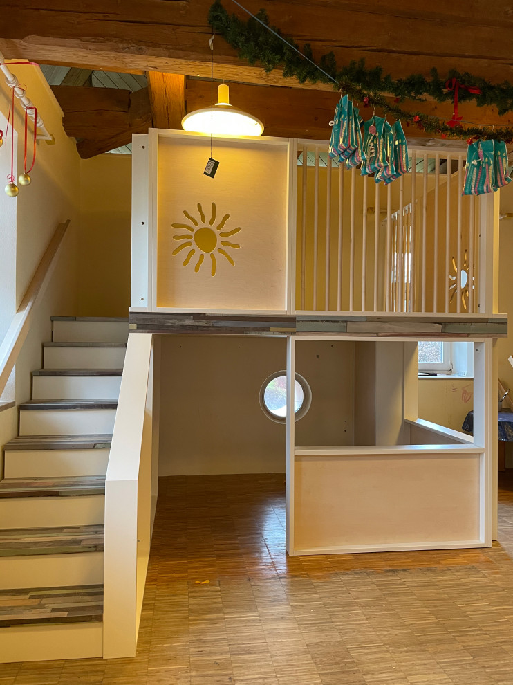 Skandinavisk inredning av ett mellanstort könsneutralt småbarnsrum kombinerat med lekrum, med vita väggar, laminatgolv och flerfärgat golv