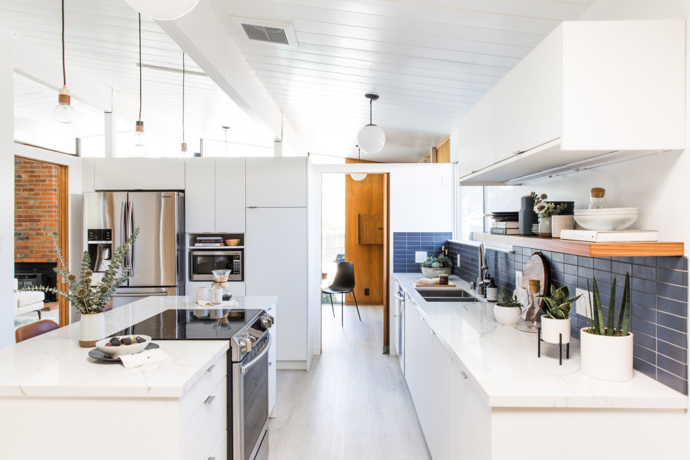 Mid-sized midcentury l-shaped kitchen in San Francisco with an undermount sink, flat-panel cabinets, white cabinets, quartz benchtops, blue splashback, ceramic splashback, stainless steel appliances, vinyl floors, with island, white benchtop and exposed beam.