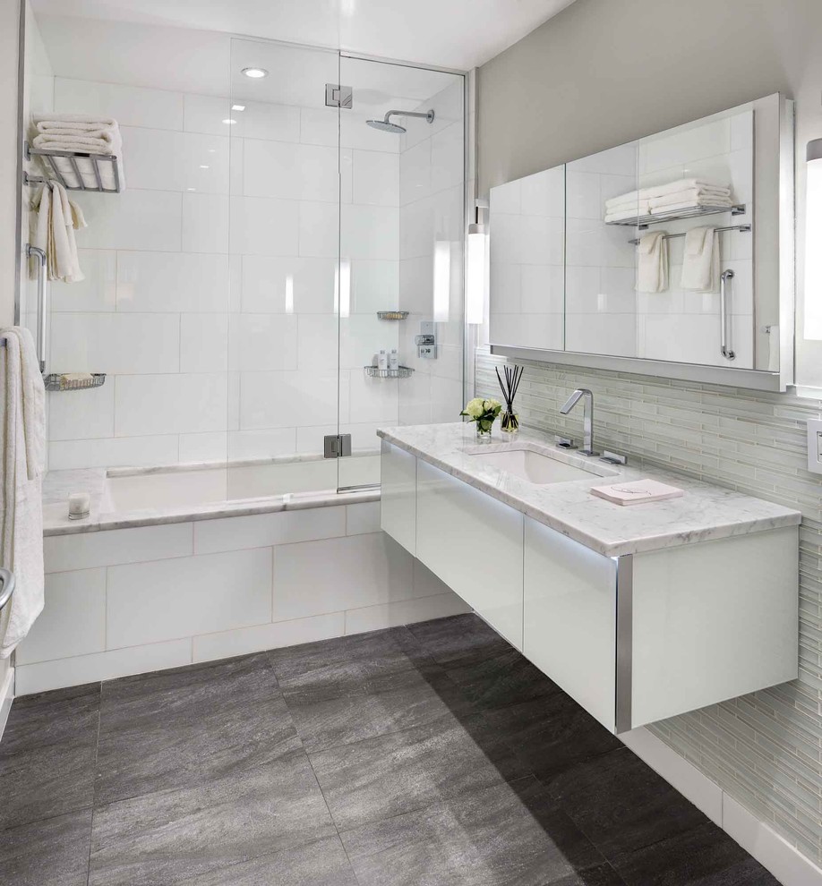 Design ideas for a large modern master bathroom in New York with flat-panel cabinets, white cabinets, a shower/bathtub combo, stone slab, a drop-in sink, an alcove tub, brown walls, porcelain floors, grey floor and a hinged shower door.