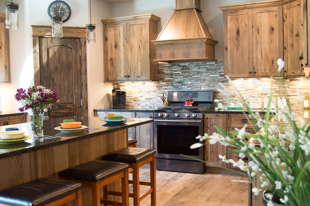 Eat-in kitchen - rustic u-shaped beige floor eat-in kitchen idea with shaker cabinets, brown cabinets, granite countertops, brown backsplash, stainless steel appliances, an island and gray countertops