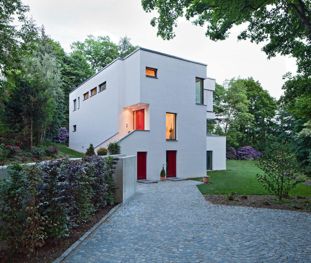 Photo of a mid-sized contemporary three-storey white exterior in Dresden with a flat roof.