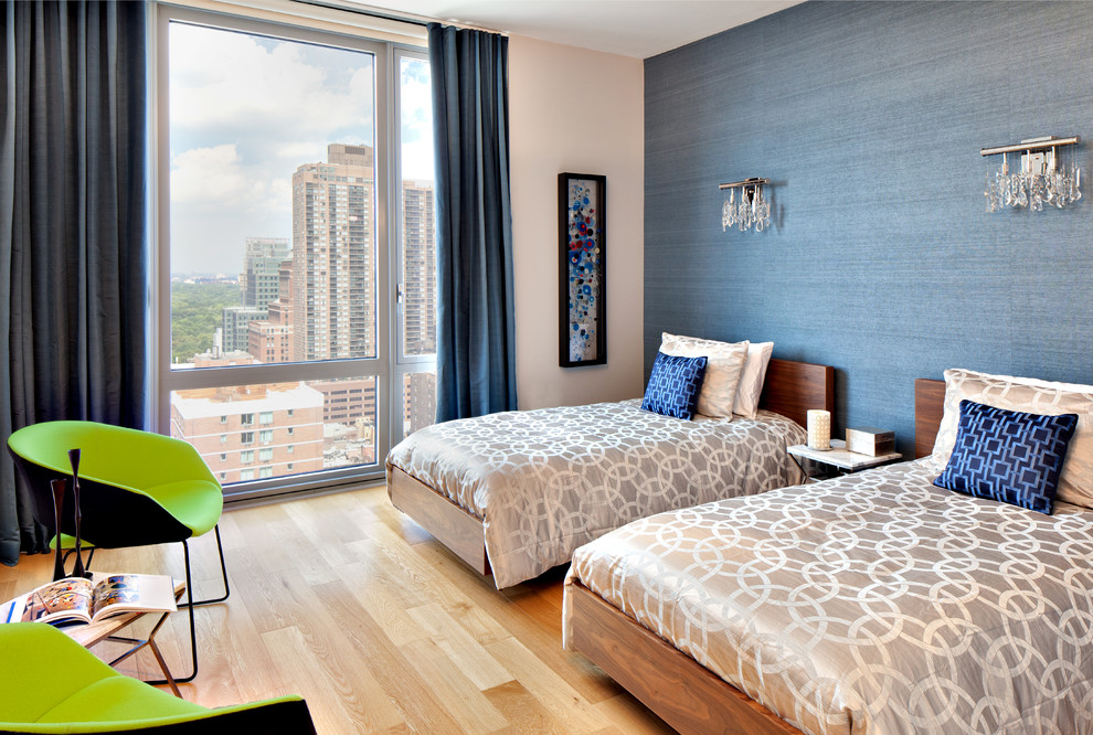 Contemporary guest bedroom in New York with blue walls and light hardwood floors.