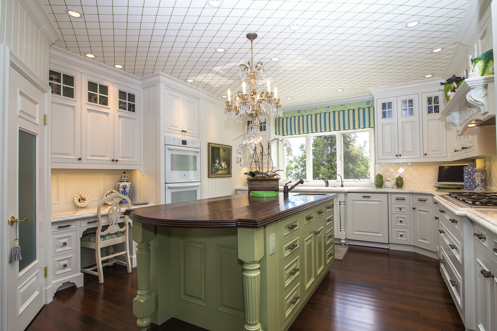 This is an example of a traditional u-shaped separate kitchen in Orange County with raised-panel cabinets, white cabinets, white splashback, panelled appliances, dark hardwood floors and with island.