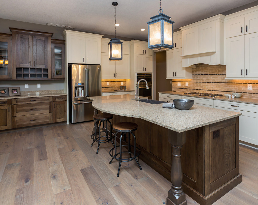 Kitchen - large transitional medium tone wood floor kitchen idea with a farmhouse sink, shaker cabinets, white cabinets, brown backsplash, stone tile backsplash, stainless steel appliances and an island