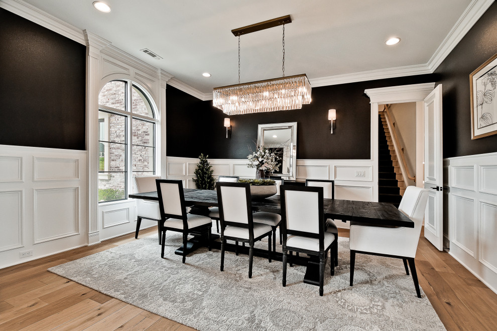 This is an example of a large transitional separate dining room in Other with black walls, light hardwood floors and decorative wall panelling.