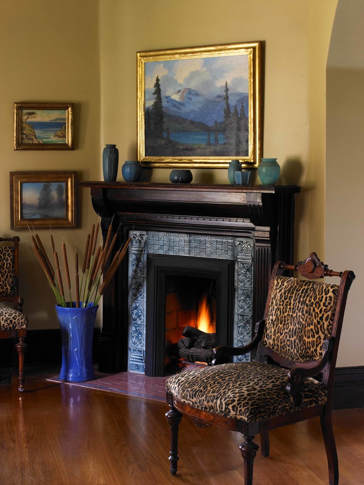 Photo of a traditional formal living room in Los Angeles with yellow walls, light hardwood floors, a corner fireplace, a wood fireplace surround and no tv.
