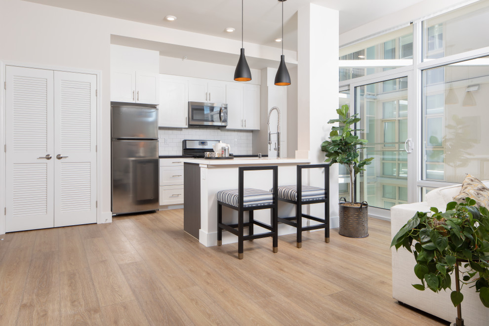 Design ideas for a small contemporary galley kitchen in San Diego with white splashback, subway tile splashback, stainless steel appliances, vinyl floors, with island, yellow floor, white benchtop, shaker cabinets and white cabinets.