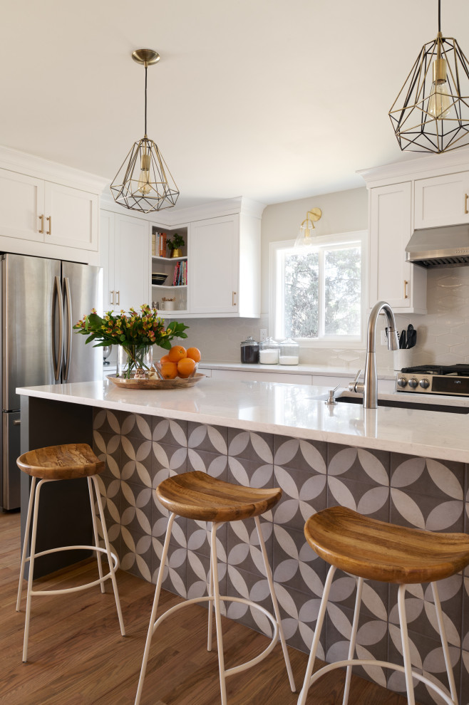 Idéer för att renovera ett mellanstort 60 tals grå grått kök, med en undermonterad diskho, skåp i shakerstil, vita skåp, bänkskiva i kvarts, grått stänkskydd, stänkskydd i keramik, rostfria vitvaror, ljust trägolv, en köksö och brunt golv