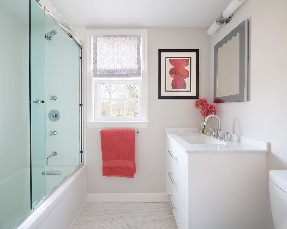 This is an example of a transitional bathroom in New York with white cabinets, flat-panel cabinets, marble benchtops, an alcove tub, a shower/bathtub combo, beige walls and mosaic tile floors.