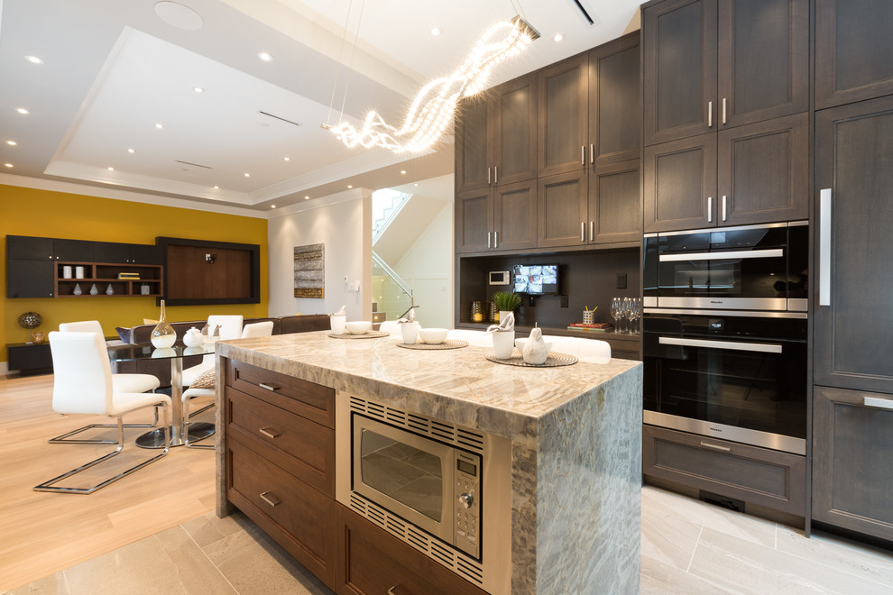Mid-sized contemporary u-shaped open plan kitchen in Vancouver with recessed-panel cabinets, dark wood cabinets, granite benchtops, multi-coloured splashback, marble splashback, stainless steel appliances, porcelain floors and with island.