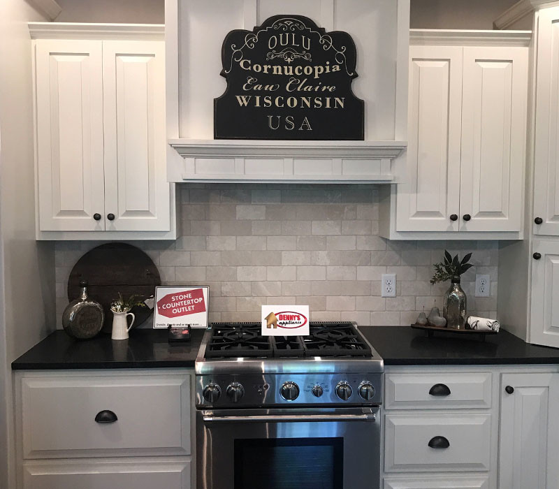 Kitchen - mid-sized transitional kitchen idea in Minneapolis with raised-panel cabinets, white cabinets, solid surface countertops, beige backsplash, subway tile backsplash, stainless steel appliances and black countertops