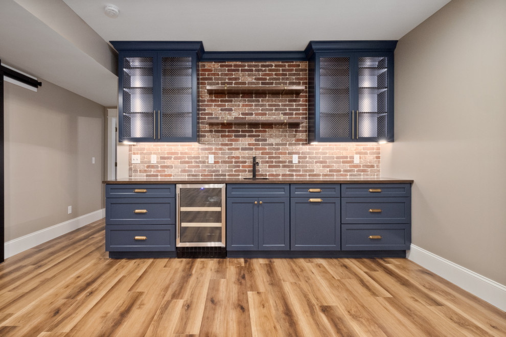 Design ideas for an expansive country single-wall wet bar in St Louis with an undermount sink, recessed-panel cabinets, blue cabinets, brown splashback, brick splashback and light hardwood floors.