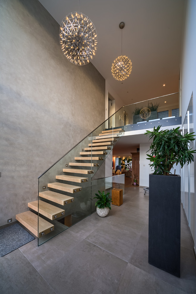 Contemporary wood straight staircase in Essen with open risers and glass railing.