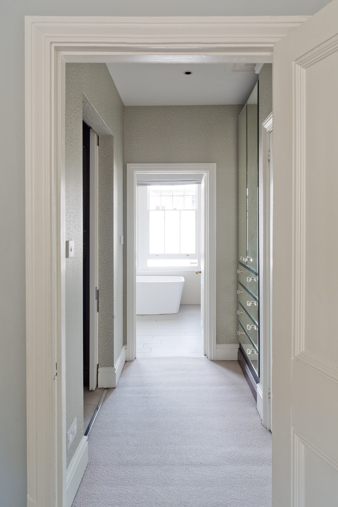 Photo of a mid-sized contemporary gender-neutral walk-in wardrobe in London with carpet, white floor, open cabinets and dark wood cabinets.