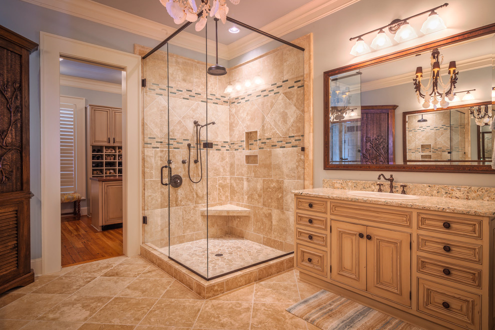 Inspiration for a large traditional master bathroom in Charleston with beige cabinets, beige tile, brown tile, terrazzo benchtops, blue walls, travertine floors, a drop-in sink, raised-panel cabinets, a corner shower, matchstick tile, beige floor and a hinged shower door.