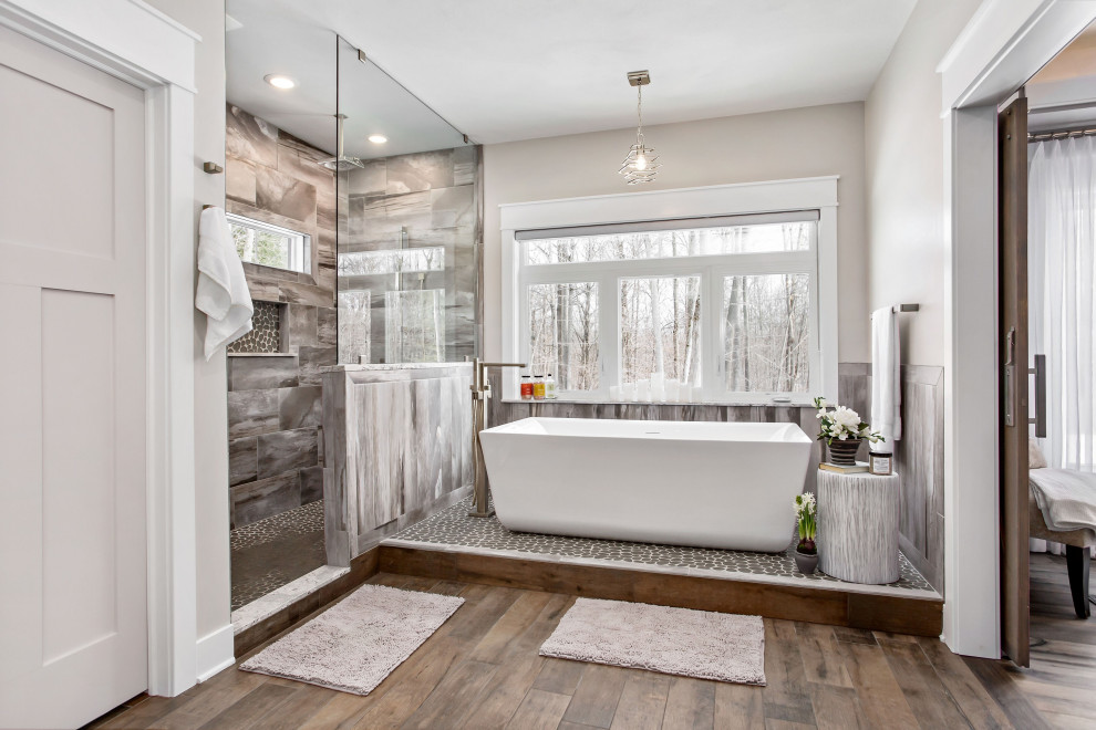 Design ideas for a country master bathroom in New York with a freestanding tub, gray tile, grey walls, dark hardwood floors, brown floor and a niche.