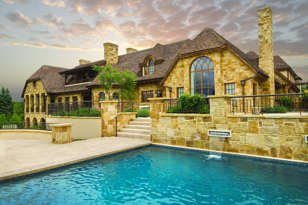 This is an example of an expansive traditional two-storey beige exterior in Denver with a hip roof and a tile roof.