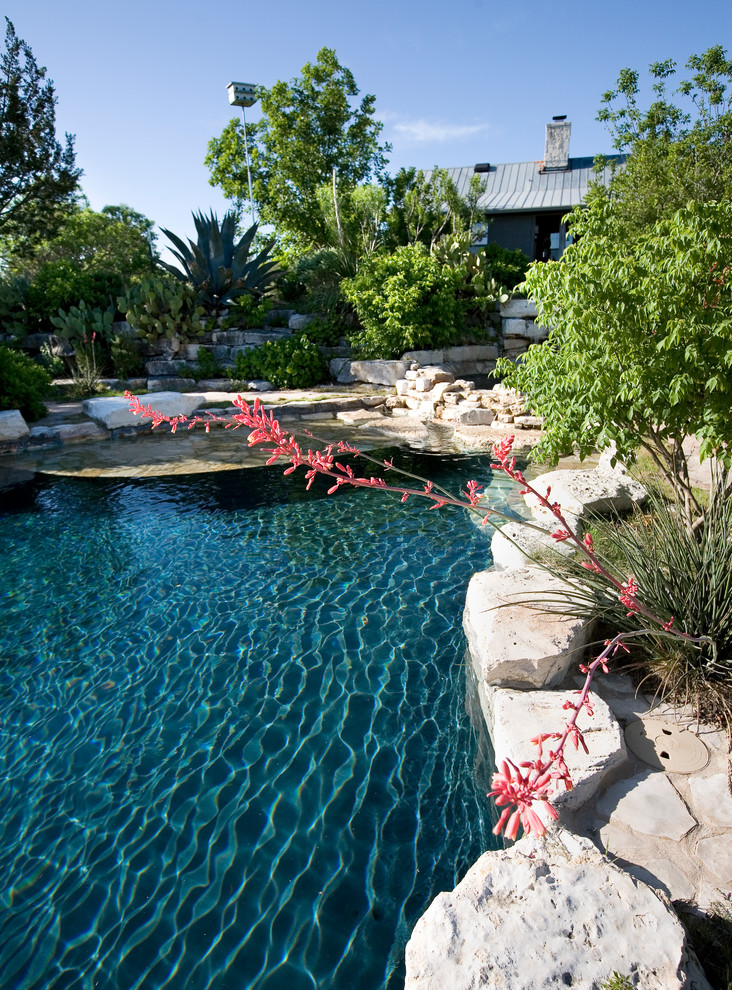 Example of a mid-sized country backyard stone and custom-shaped natural hot tub design in Austin