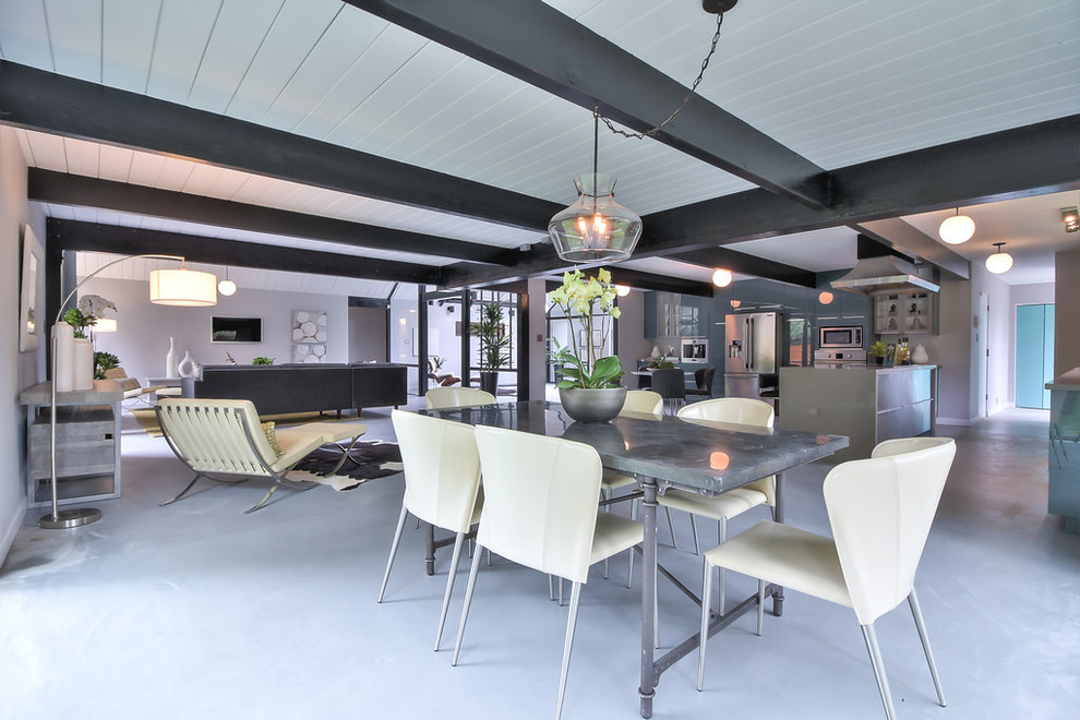 This is an example of a large midcentury open plan dining in Other with grey walls, concrete floors, no fireplace and grey floor.