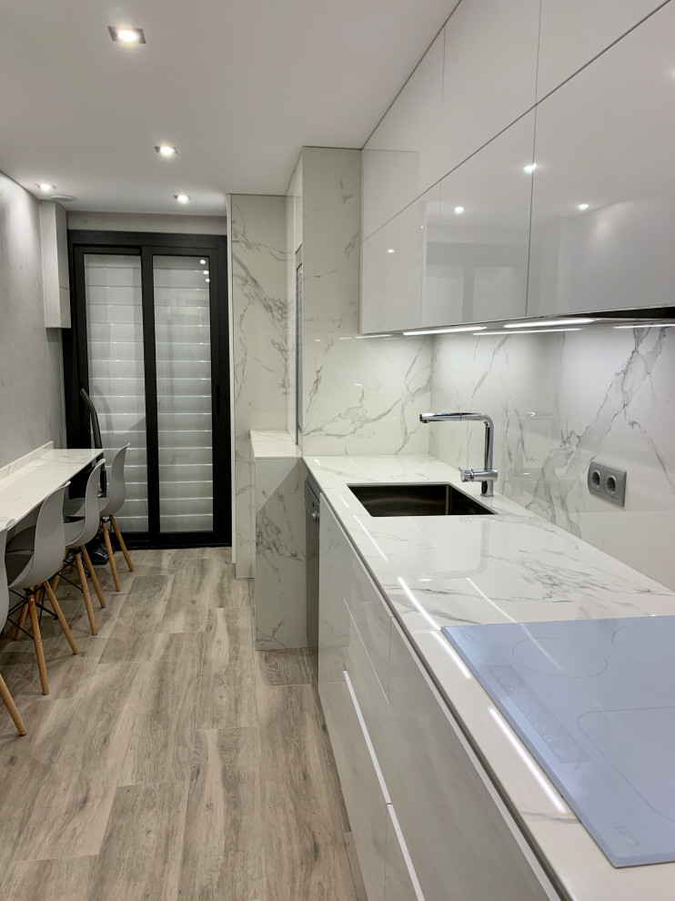 Design ideas for a mid-sized modern galley separate kitchen in Barcelona with an undermount sink, white cabinets, tile benchtops, stainless steel appliances, porcelain floors, no island and white benchtop.