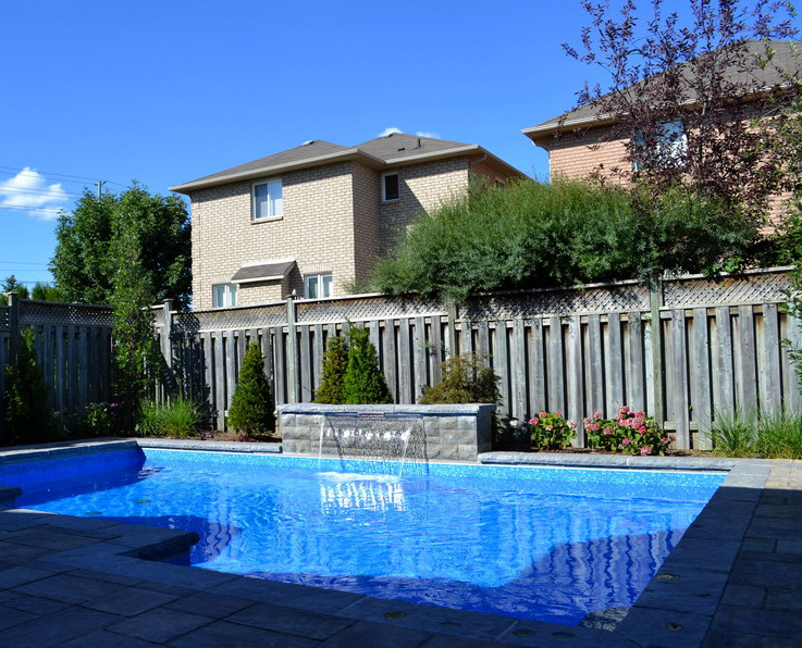 Large traditional backyard custom-shaped pool in Toronto with a water feature.