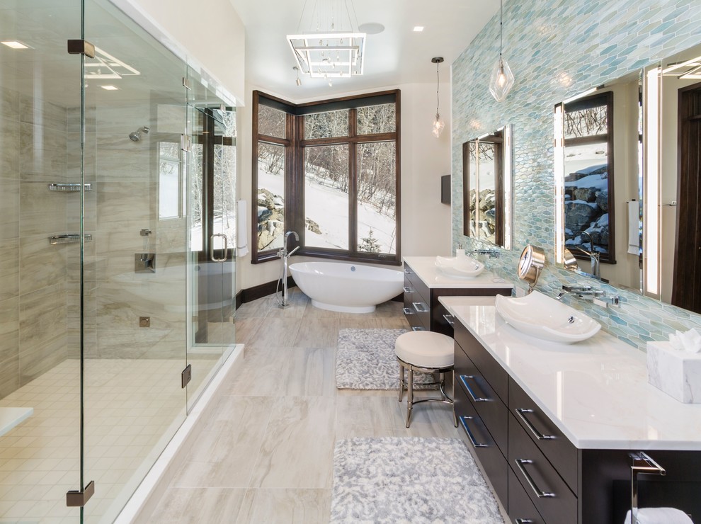 Design ideas for a contemporary master bathroom in Denver with flat-panel cabinets, dark wood cabinets, a freestanding tub, a corner shower, blue tile, beige walls, a vessel sink, beige floor and a hinged shower door.