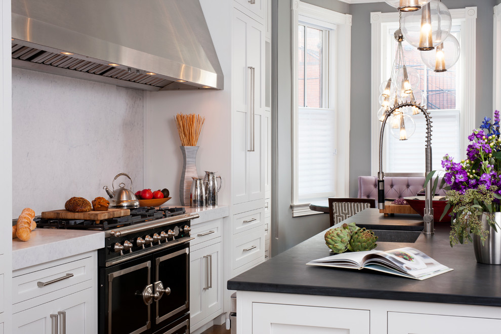 Large transitional galley eat-in kitchen in DC Metro with a single-bowl sink, shaker cabinets, white cabinets, soapstone benchtops, white splashback, stone slab splashback, dark hardwood floors, with island and black appliances.