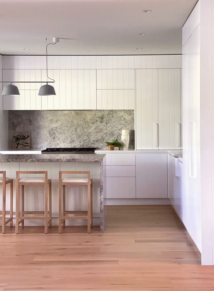 Large contemporary kitchen in Sydney with white cabinets and limestone benchtops.