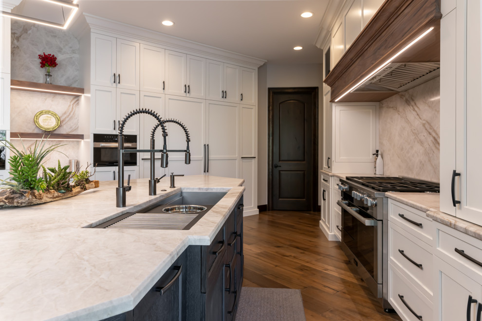 Large transitional medium tone wood floor and brown floor open concept kitchen photo with a double-bowl sink, flat-panel cabinets, white cabinets, quartzite countertops, beige backsplash, stainless steel appliances, an island and beige countertops