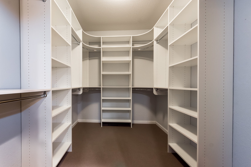 Photo of a large industrial walk-in wardrobe in Chicago with white cabinets and carpet.