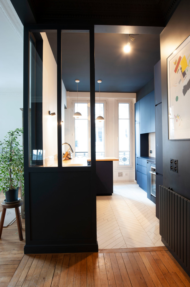 Offene, Zweizeilige Moderne Küche mit Kassettenfronten, blauen Schränken, Arbeitsplatte aus Holz, Küchenrückwand in Beige, Rückwand aus Steinfliesen und brauner Arbeitsplatte in Paris