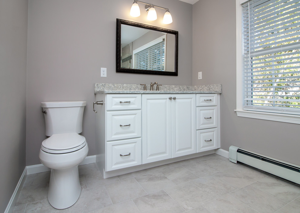 Inspiration for a mid-sized contemporary master bathroom in Manchester with raised-panel cabinets, white cabinets, an alcove shower, a two-piece toilet, white tile, porcelain tile, grey walls, porcelain floors, an undermount sink, engineered quartz benchtops, white floor, a hinged shower door and multi-coloured benchtops.